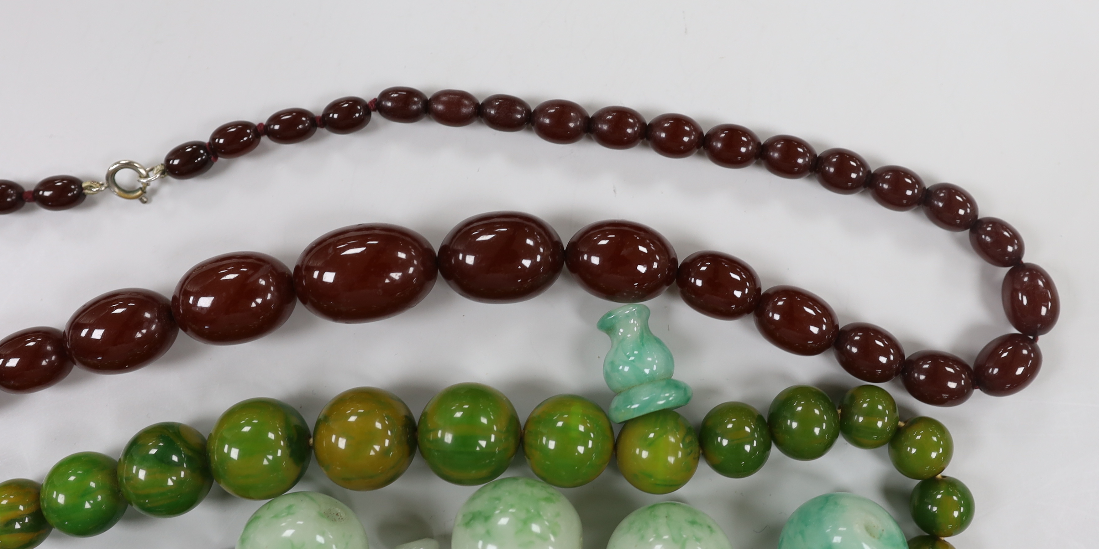 A single strand graduated simulated cherry amber necklace, one other necklace and some loose beads